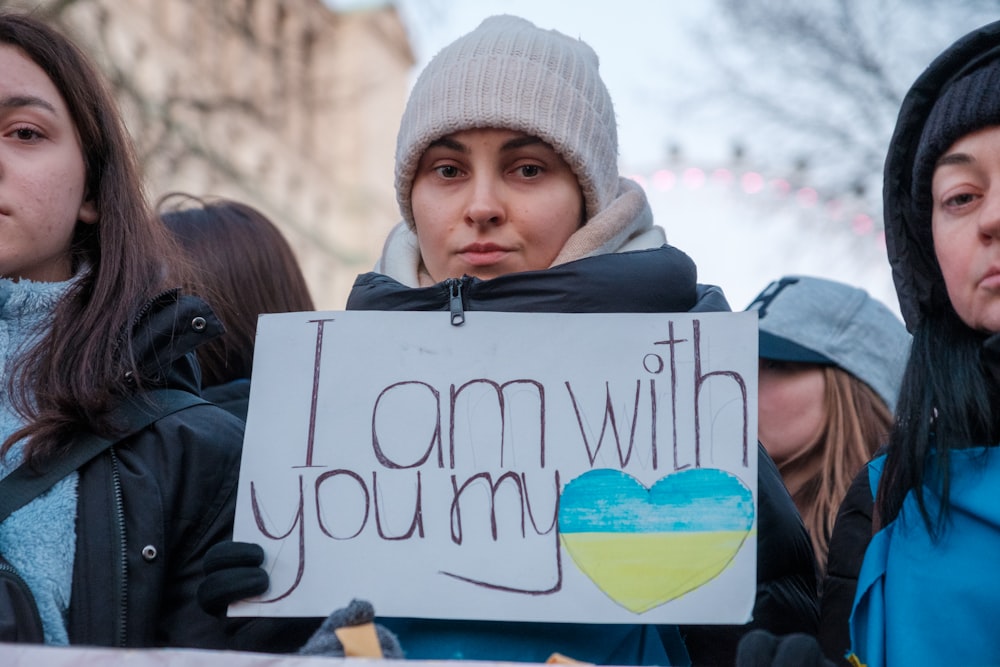 a woman holding a sign that says i am with you