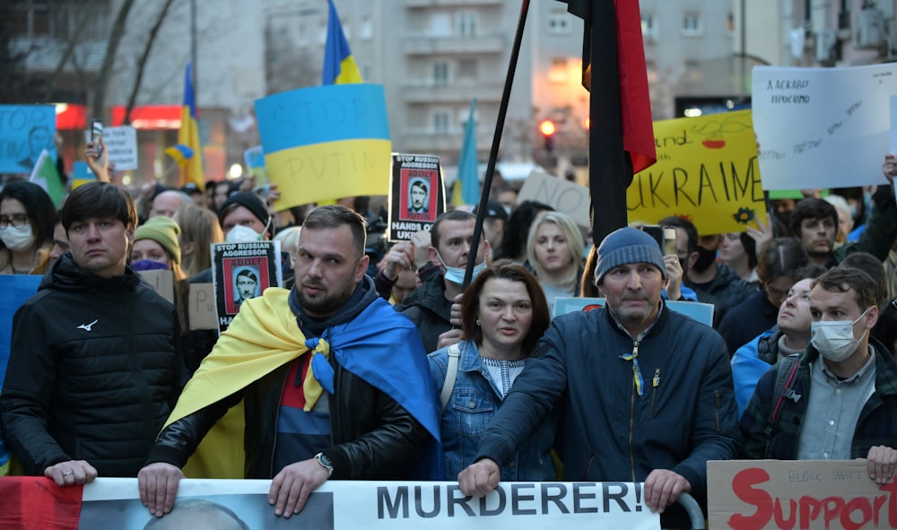 a crowd of people holding signs and wearing masks