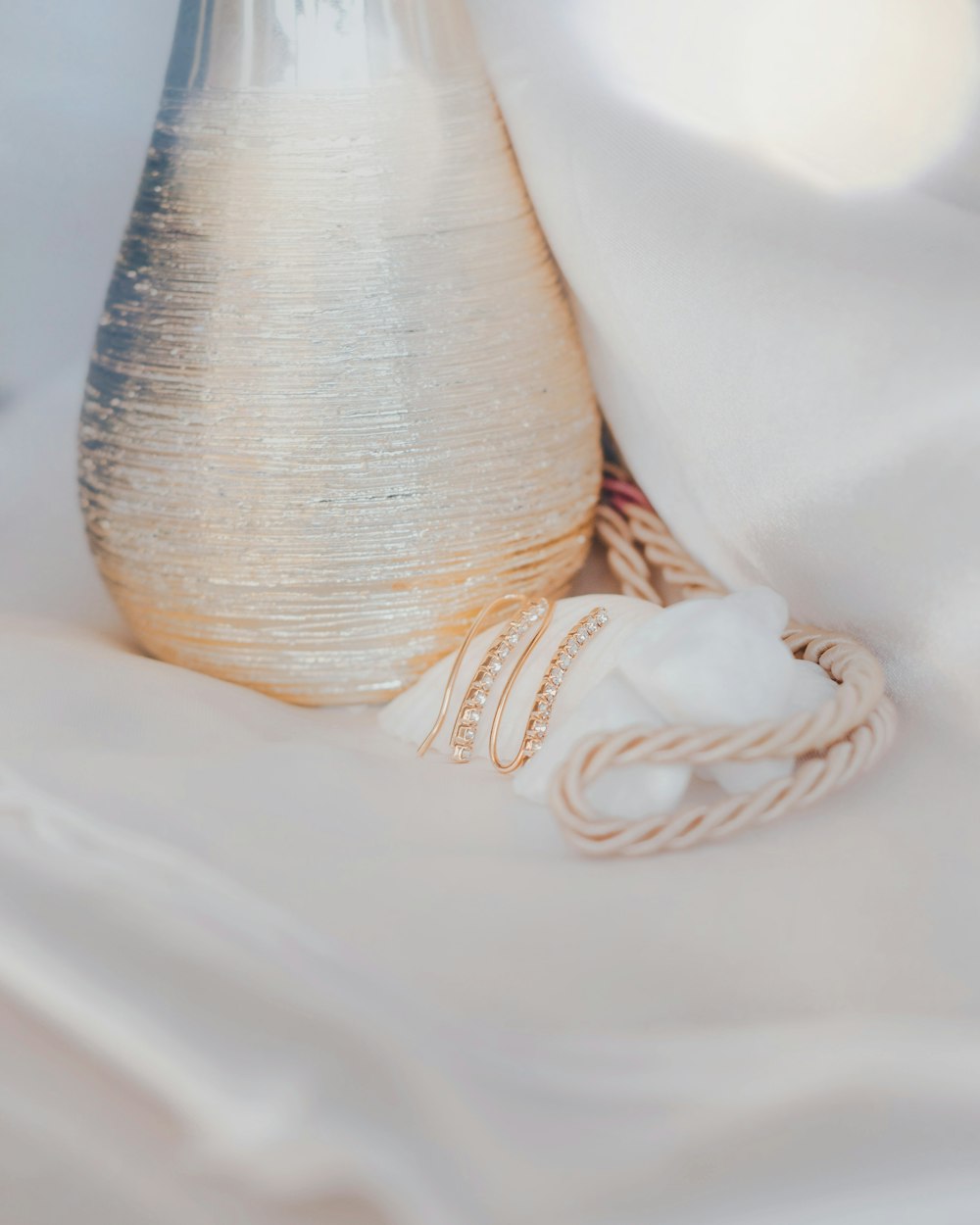 a white vase sitting on top of a white sheet