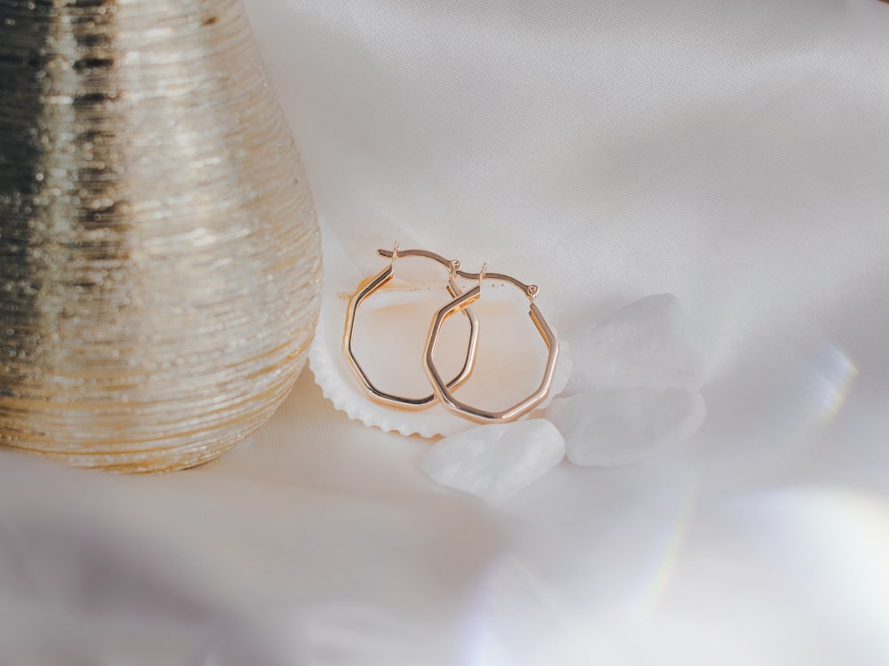 a pair of gold hoop earrings sitting on top of a white cloth