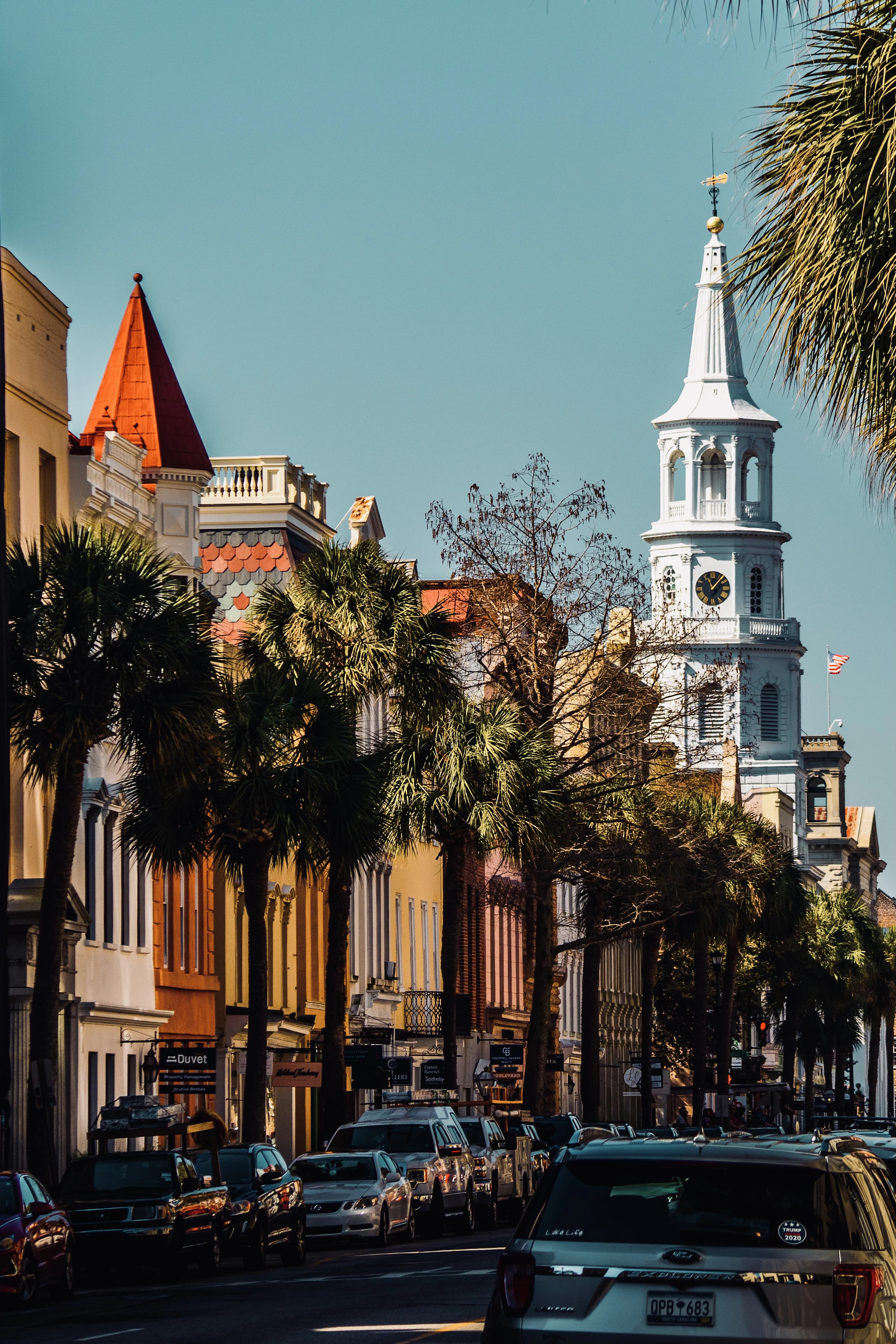 Downtown Charleston street with a historic church steeple rising above the rooftops