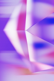 An abstract image with smooth gradients and geometric shapes, reflecting a mix of pink, purple, and blue hues. The composition features soft lines and blurred edges, creating a dreamy and ethereal atmosphere.
