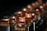 A series of metallic components with copper tops and black bases aligned in a row, reflecting ambient light. The background is softly blurred, accentuating the focus on the copper elements.