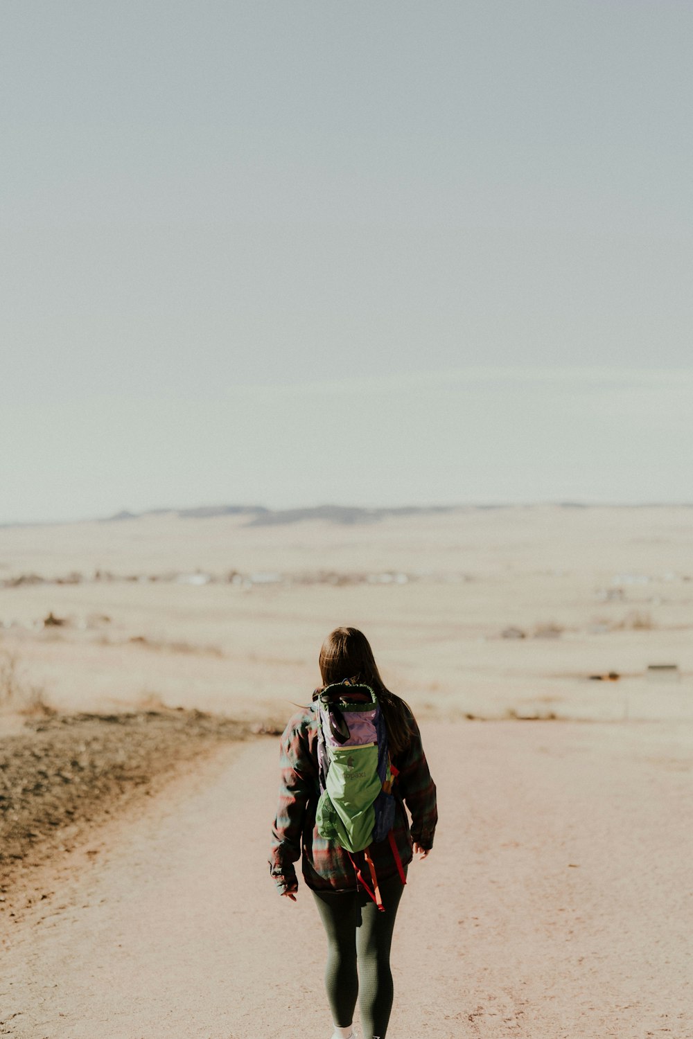 uma mulher andando por uma estrada de terra no deserto