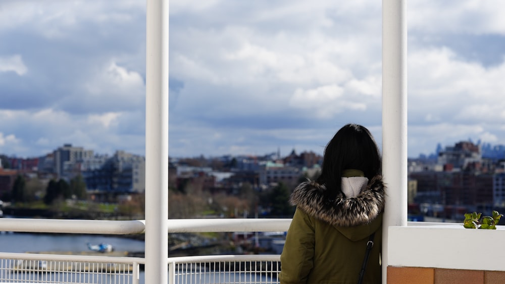 a woman standing on a balcony with a cup in her hand