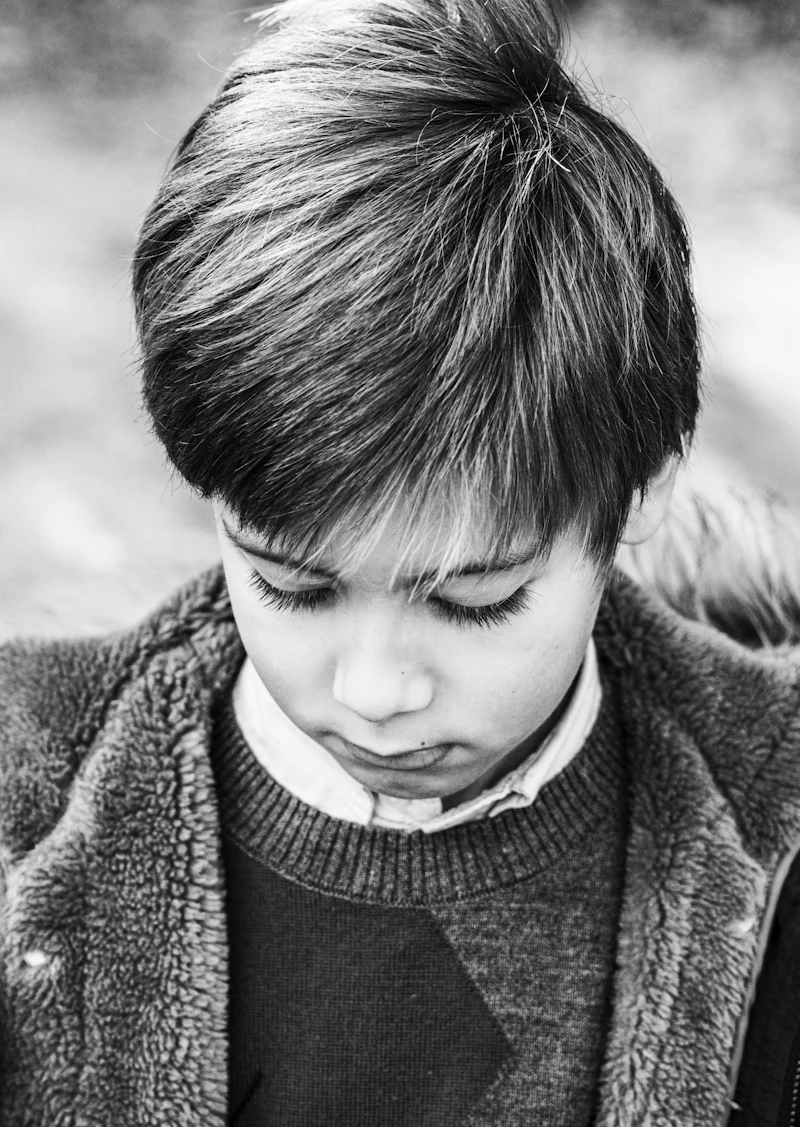 A boy with a neat, full fringe looking down