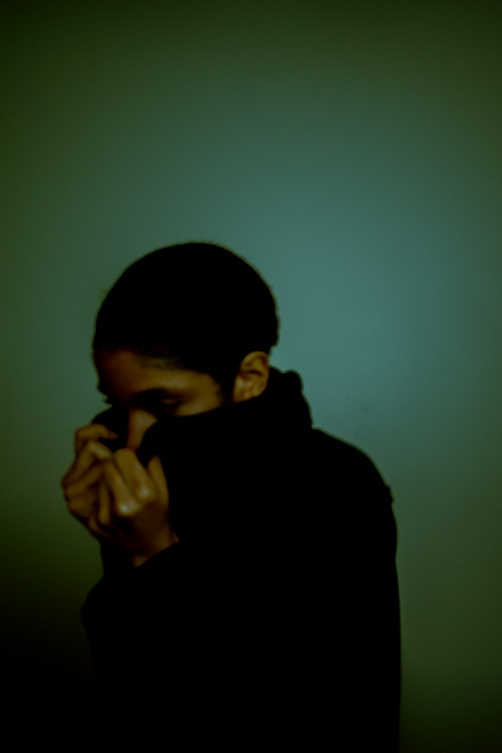 a person standing in a dark room with their hands on their face