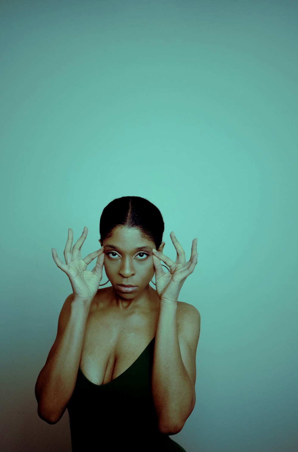 a woman in a black dress holding her hands up to her face