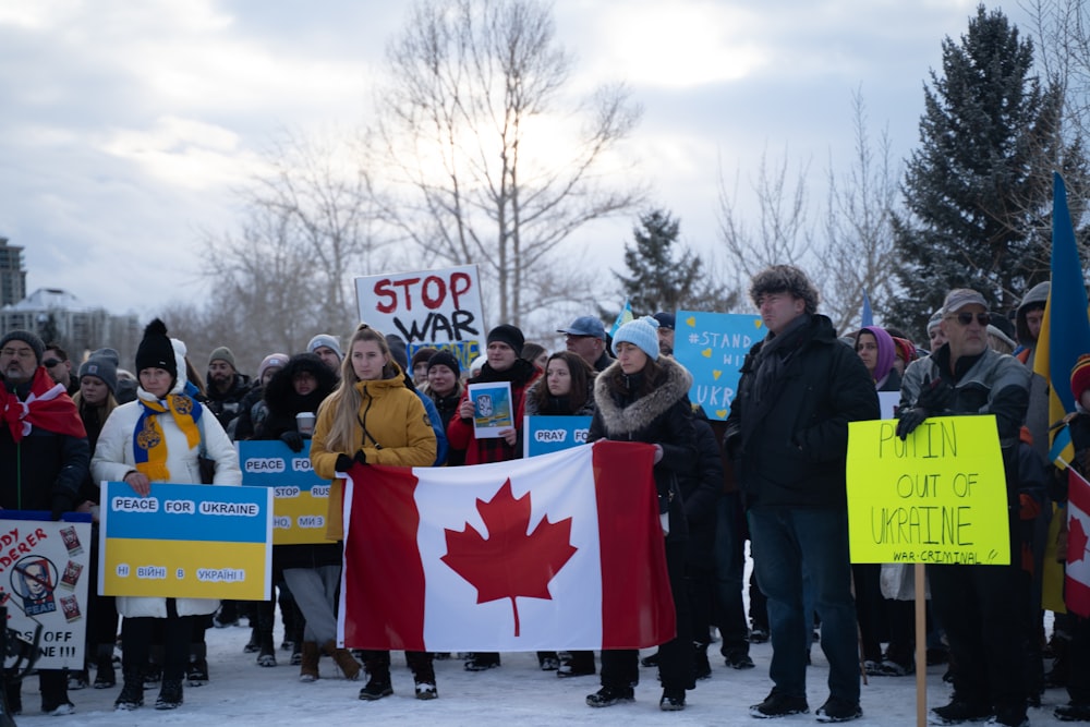 un groupe de personnes tenant des drapeaux et des pancartes canadiens