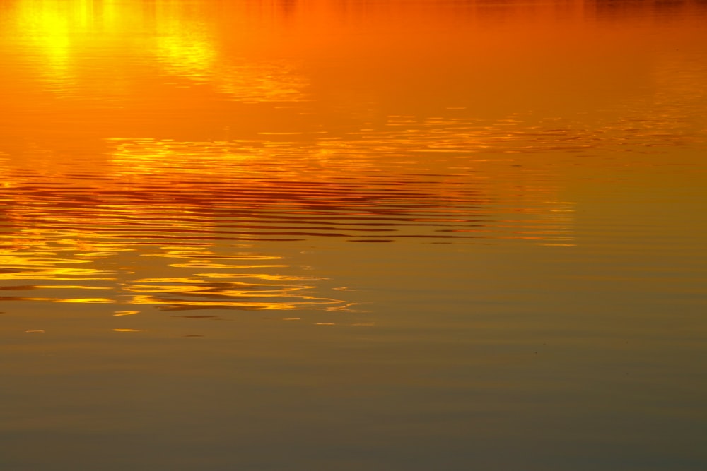 a large body of water with a sunset in the background