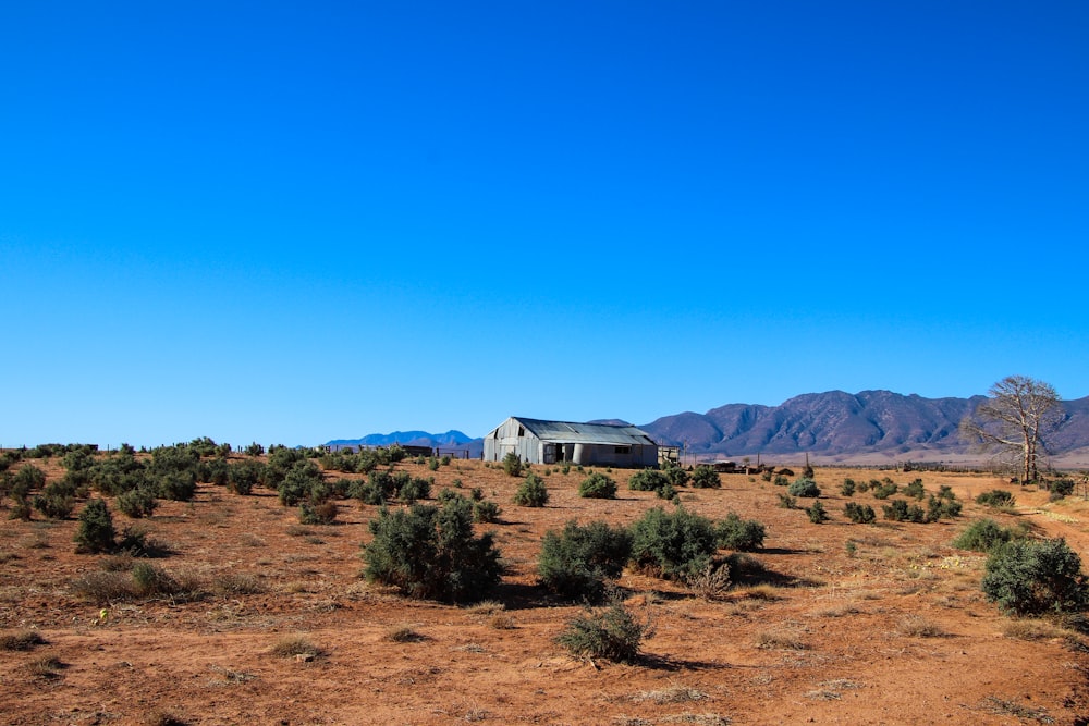 a house in the middle of a desert with mountains in the background
