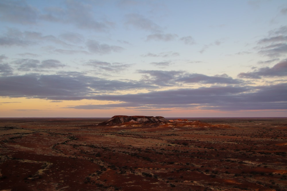 a desert landscape with a hill in the distance