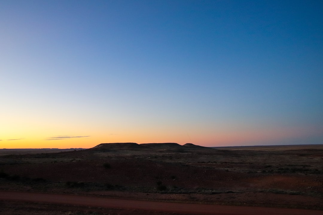 the sun is setting in the distance over the desert,