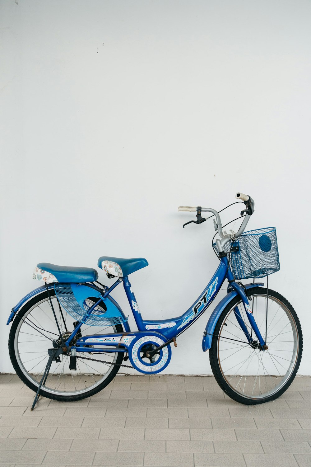 a blue bicycle parked next to a white wall