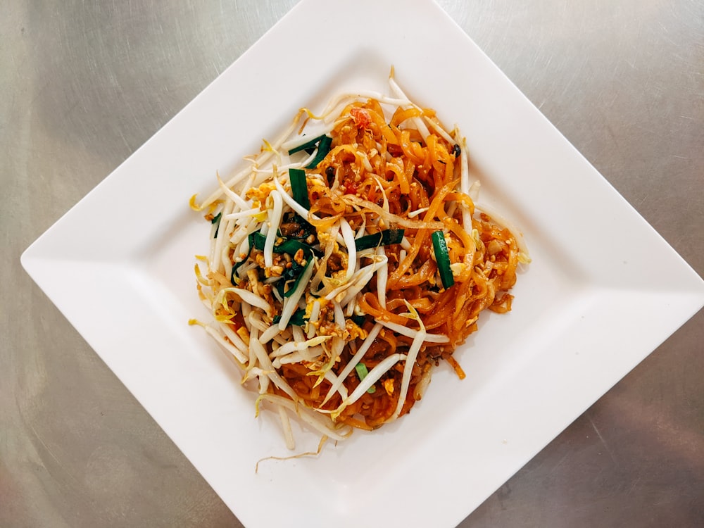 a white plate topped with noodles and vegetables