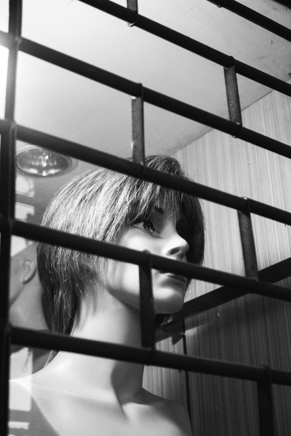 a mannequin with a short haircut behind bars