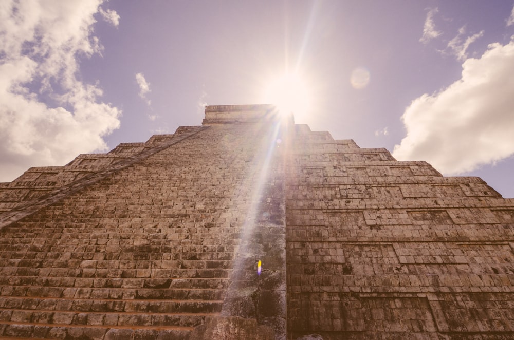 the sun shines brightly through the clouds above a pyramid