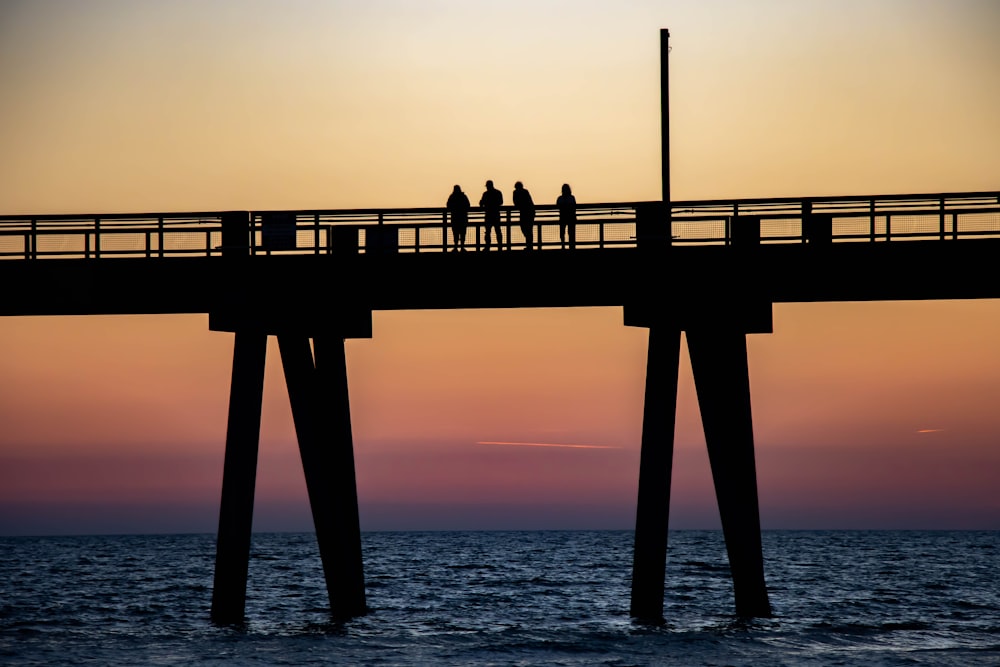 a group of people walking across a bridge over a body of water