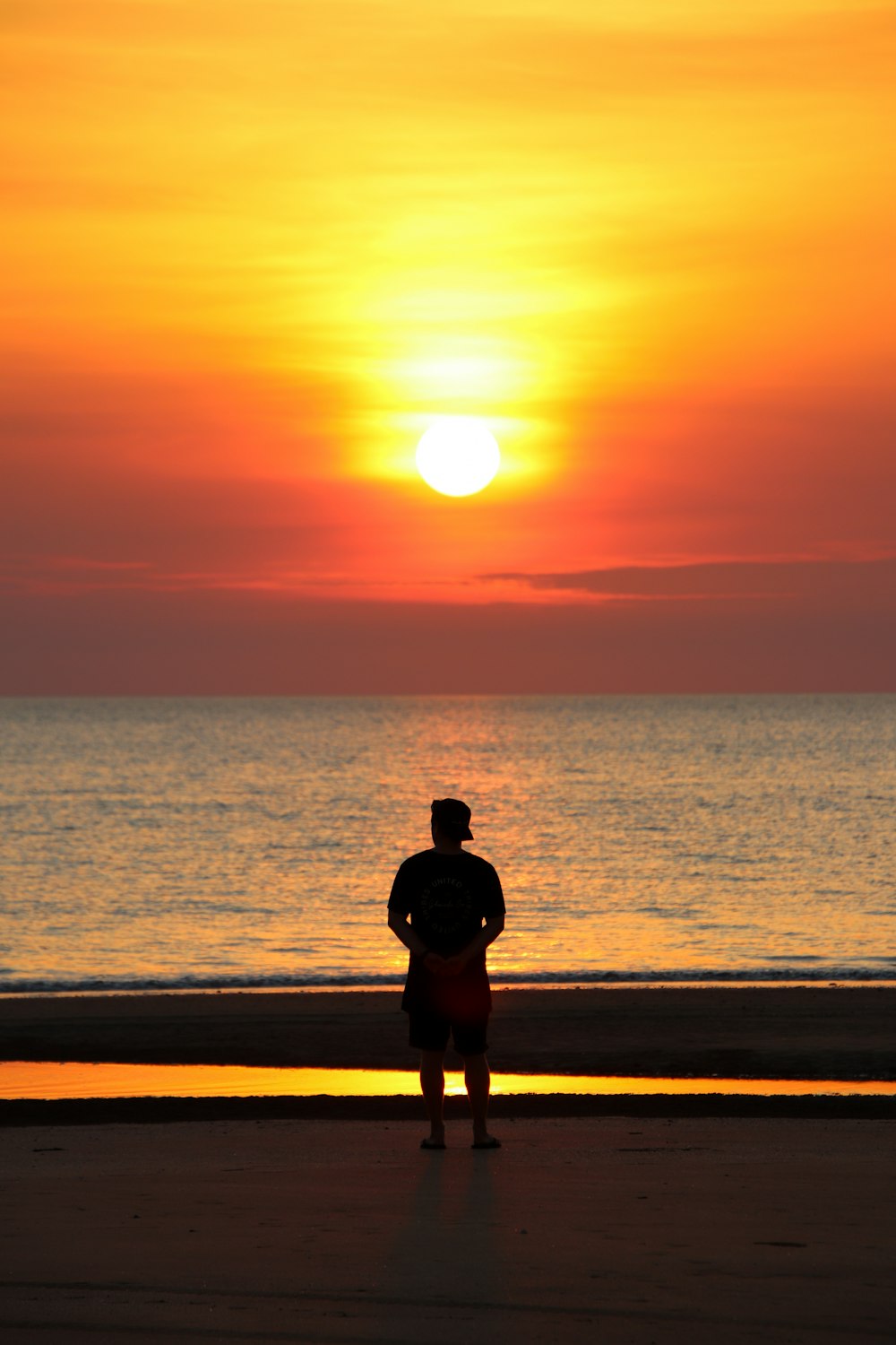 a man standing on the beach watching the sun set