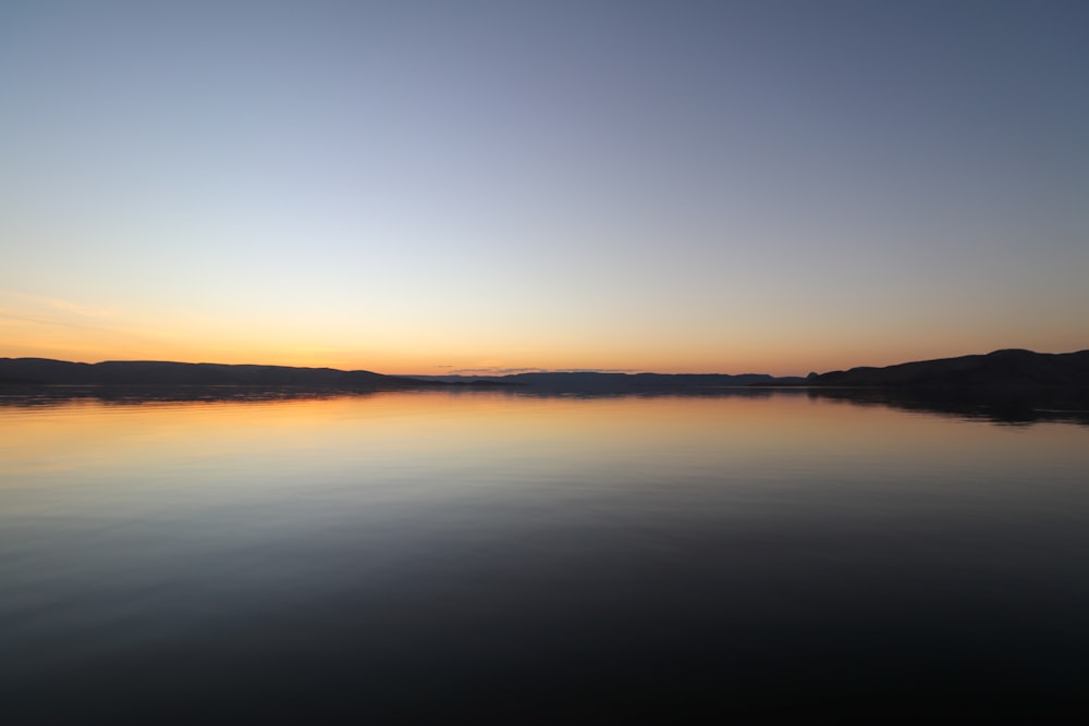 a body of water with a sunset in the background