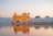 A serene Thai temple at sunset with golden light reflecting on ancient architecture.