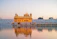 A serene Thai temple at sunset with golden light reflecting on ancient architecture.
