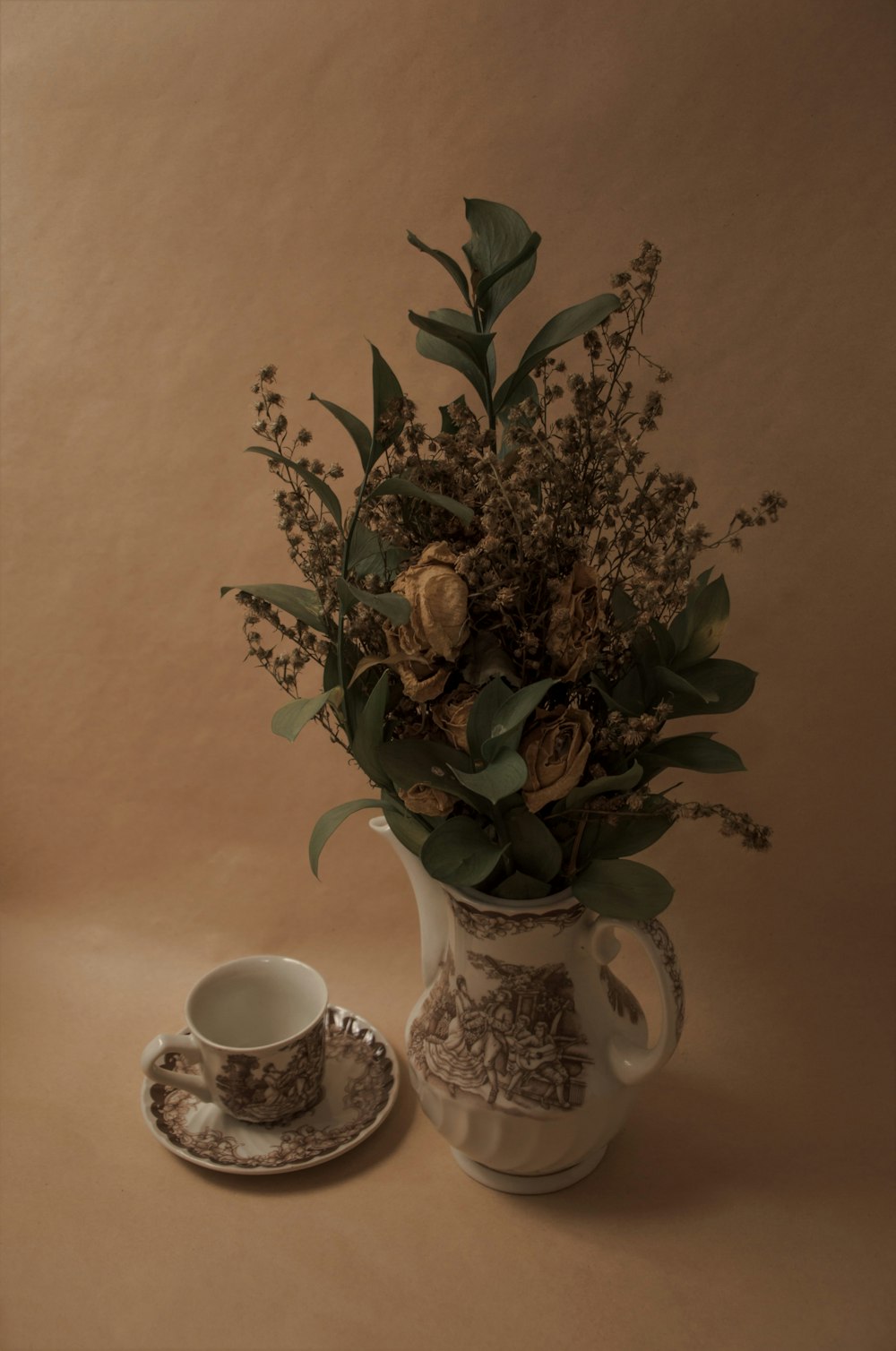 a vase with flowers and a cup on a saucer