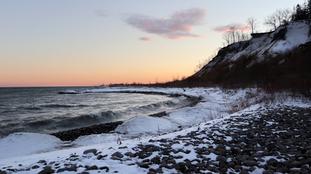 a beach covered in snow next to a cliff