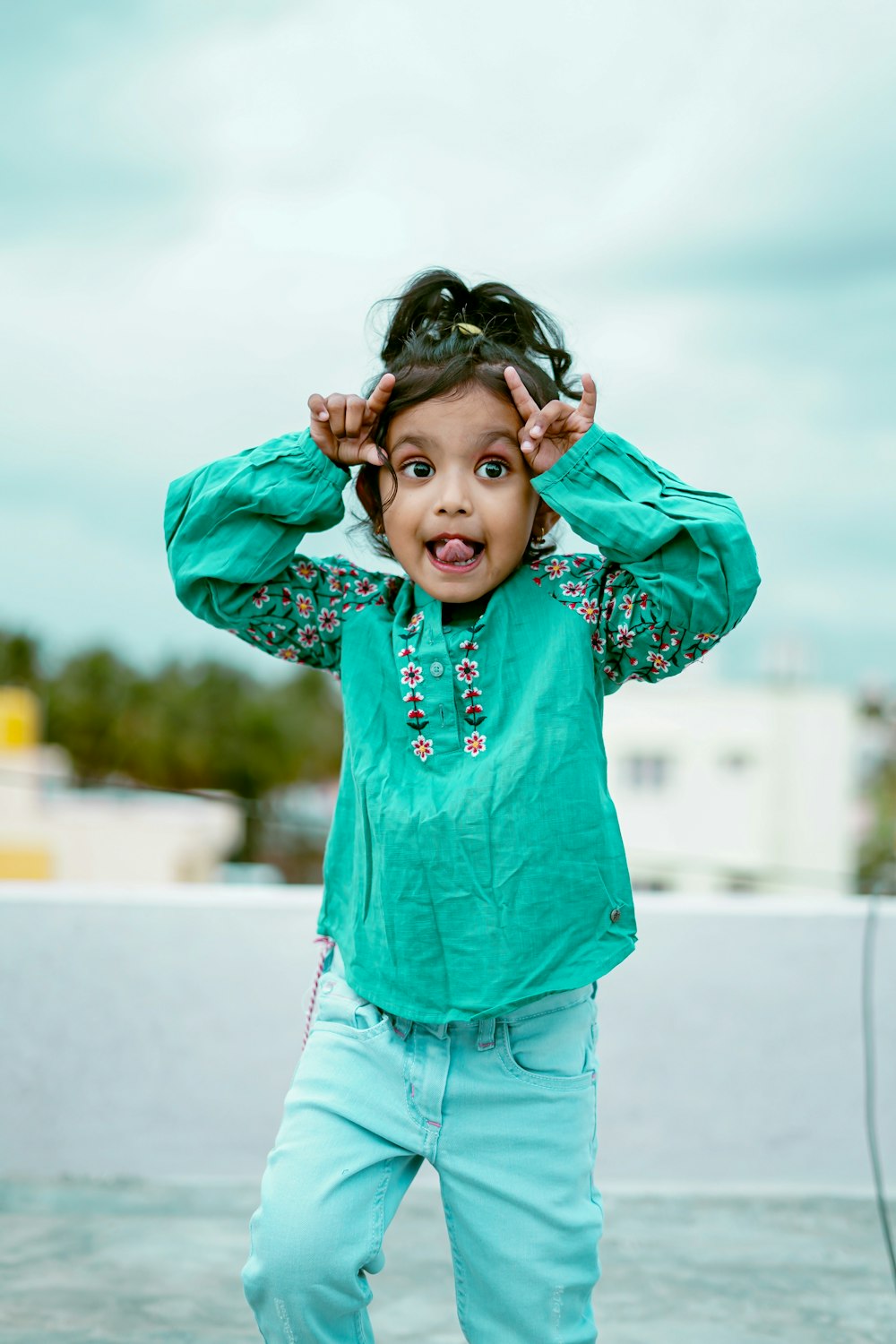 a little girl that is standing up with her hands on her head