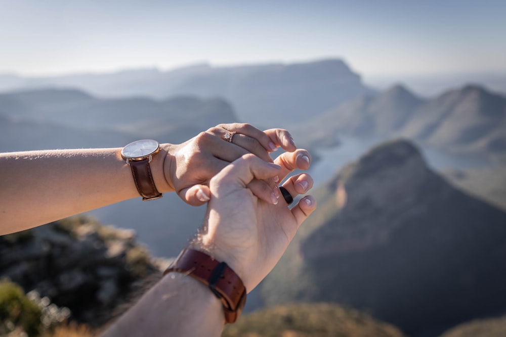 two people holding hands on top of a mountain
