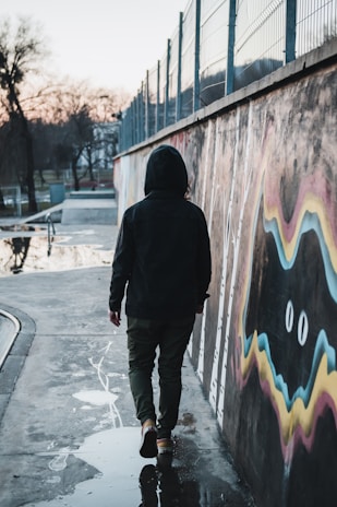 a man walking down a sidewalk next to a wall