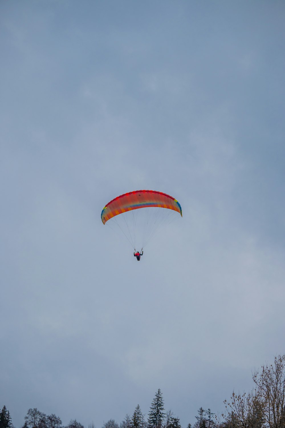 a person is parasailing in the sky on a cloudy day