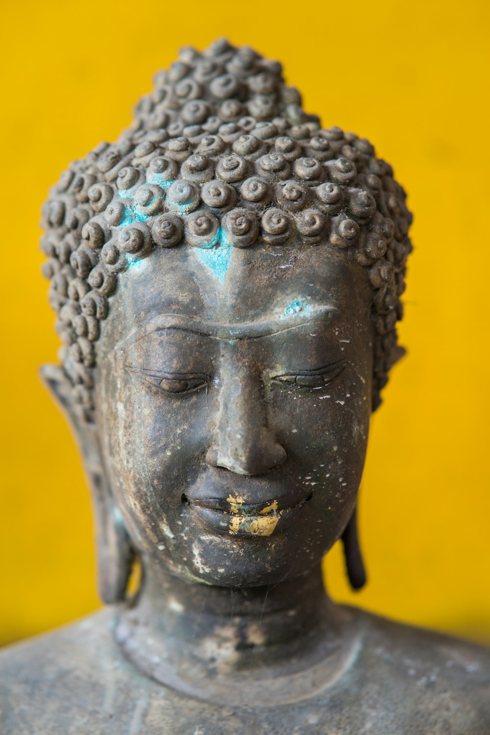 a close up of a buddha statue with a yellow background