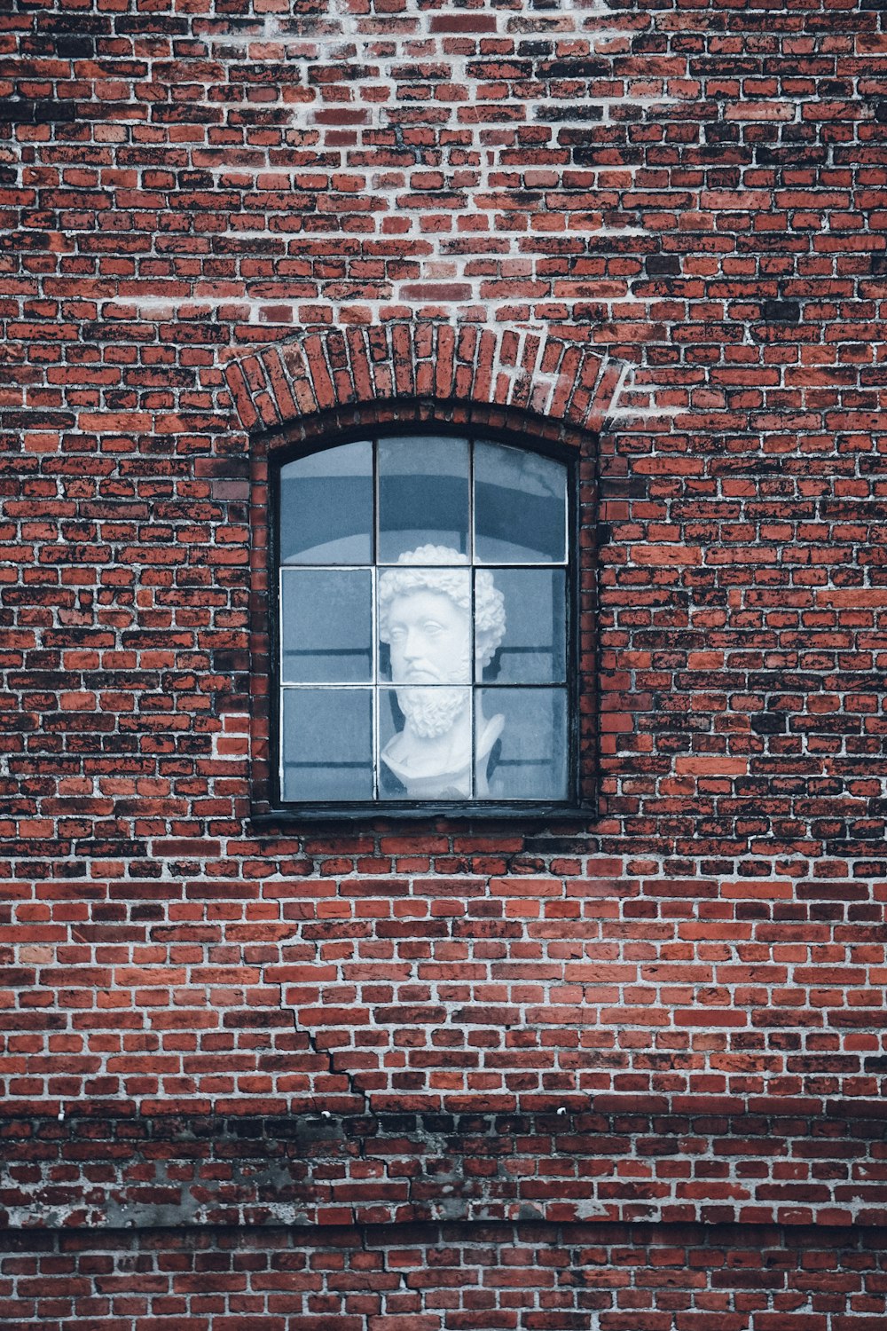 a brick building with a window and a statue in the window