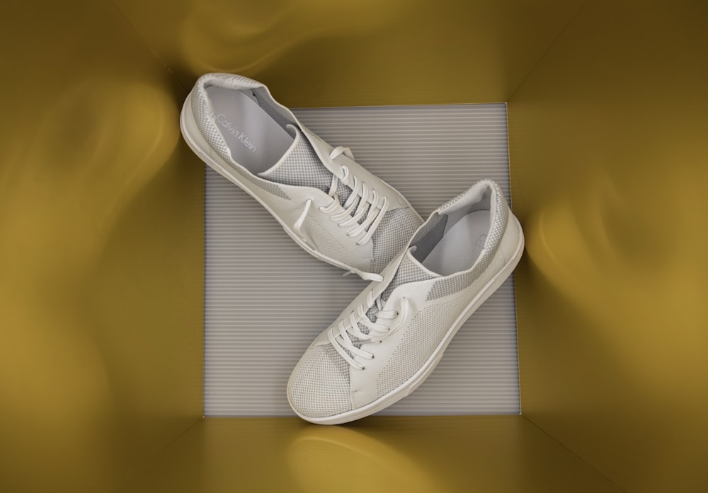 une paire de chaussures de tennis blanches posées sur un tapis