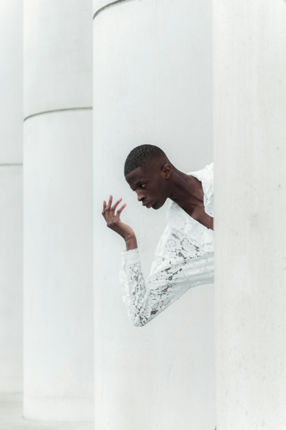 a man in a white shirt leaning against a column