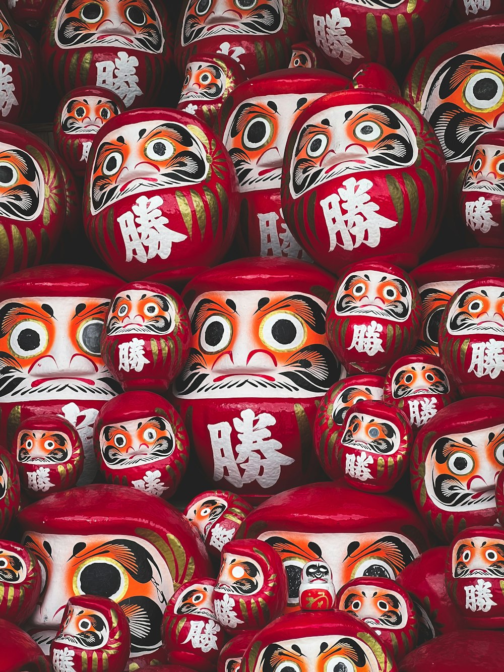 a pile of red vases with faces painted on them