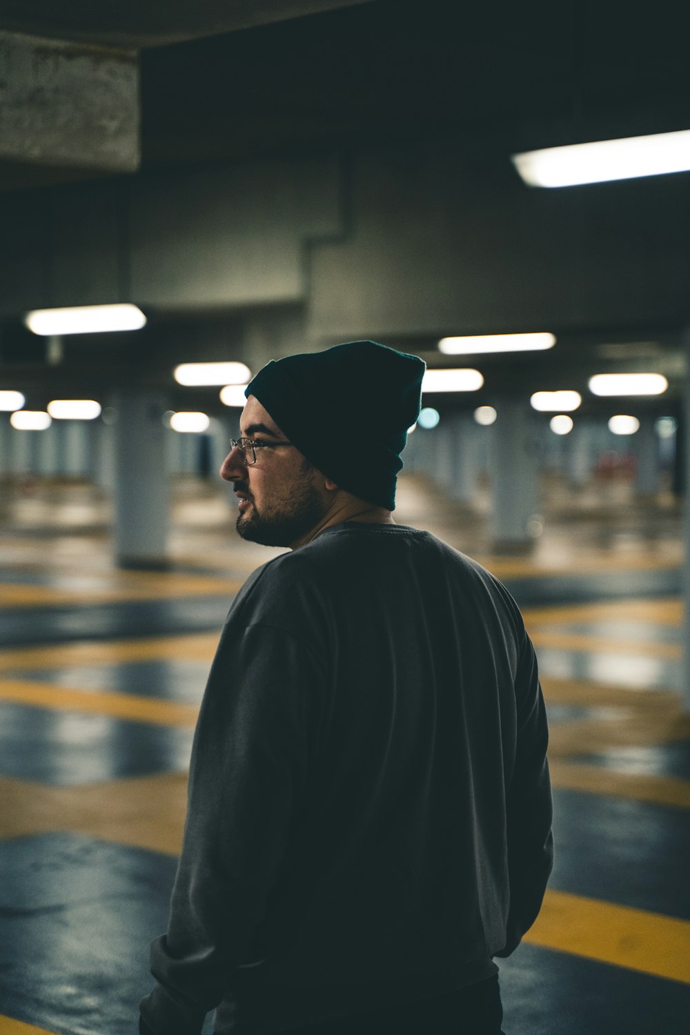 a man standing in a parking garage wearing a beanie