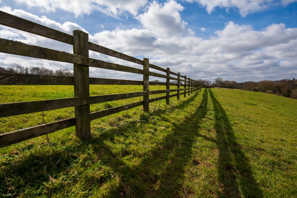 a long wooden fence in a grassy field