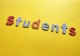 Colorful letters arranged to spell 'students' against a bright yellow background. Each letter is decorated with different patterns, such as polka dots, stripes, and checkered designs.