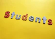 Colorful letters arranged to spell 'students' against a bright yellow background. Each letter is decorated with different patterns, such as polka dots, stripes, and checkered designs.