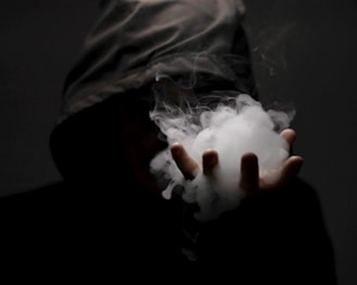 a person in a hooded jacket holding a cloud of smoke