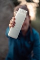 a woman holding a white bottle in her right hand