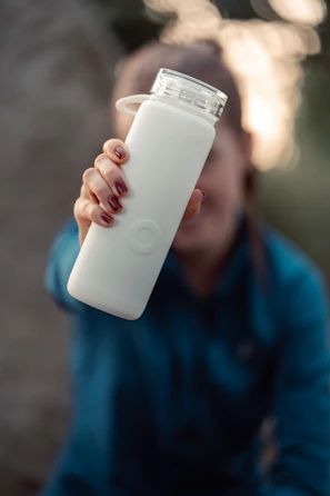 Lifestyle shot of a person holding a Noblefit bottle with a soft glow highlighting the label