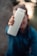 A person is holding a white water bottle prominently towards the camera, with a blurred background. The focus is on the bottle, which has a simple design with a clear lid.