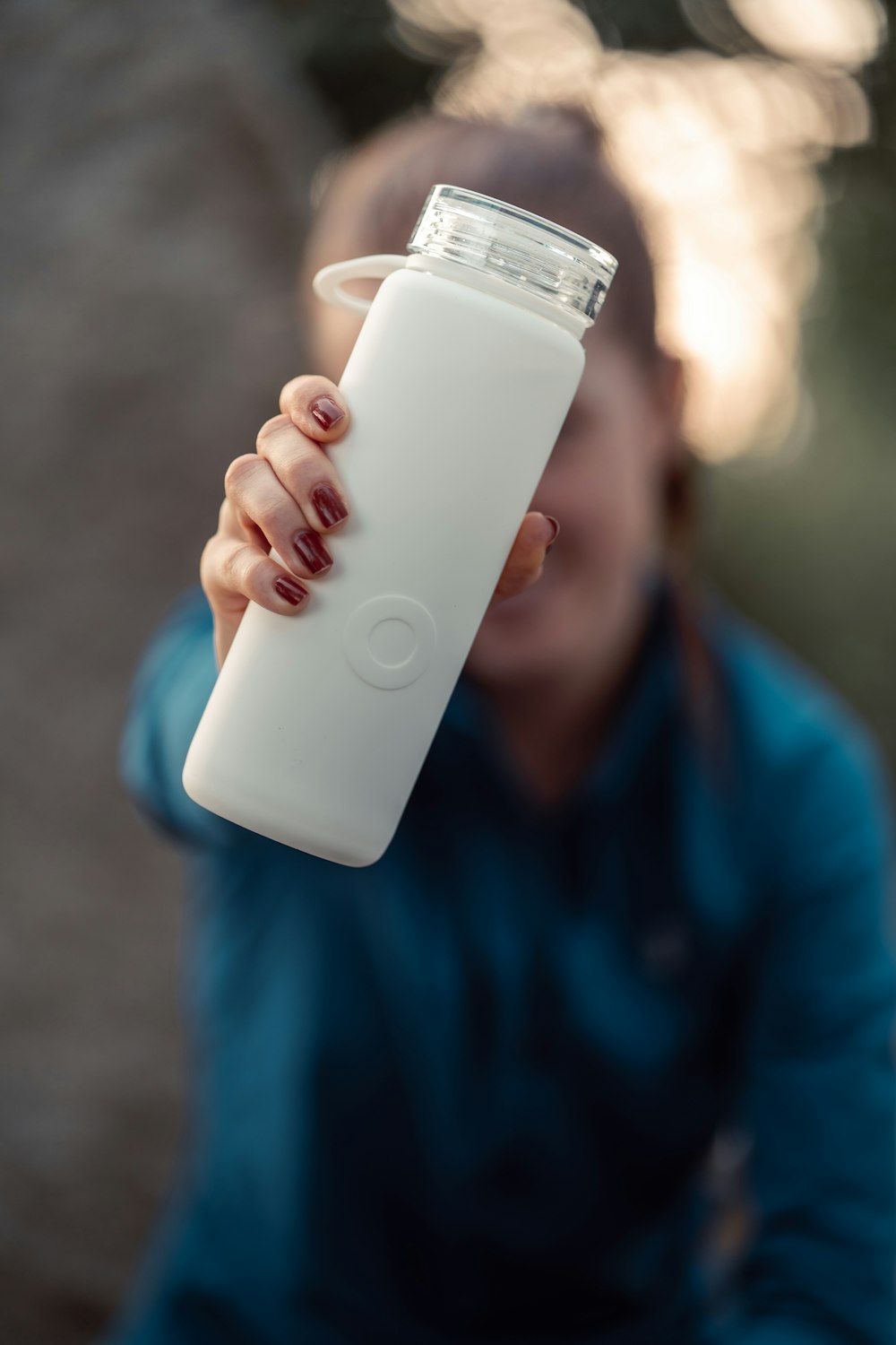 a woman holding a white bottle in her right hand