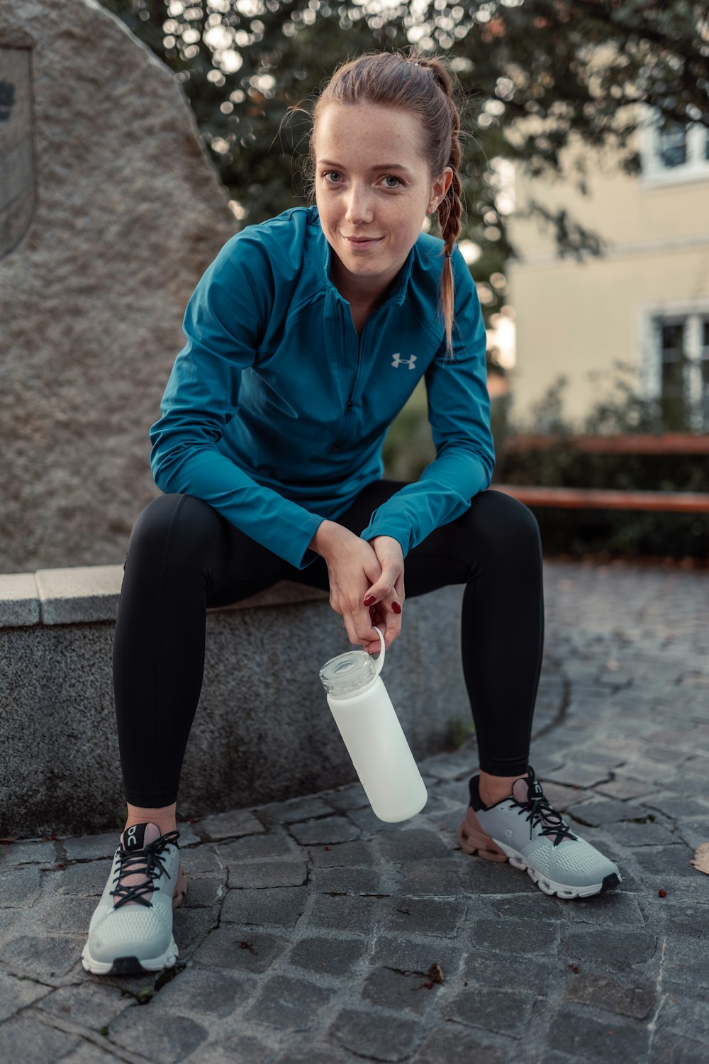 a woman sitting on a bench holding a cup