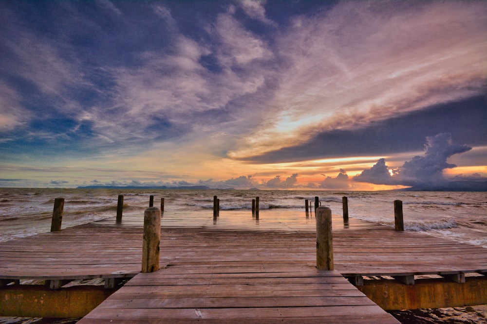 a wooden dock sitting on top of a beach under a cloudy sky