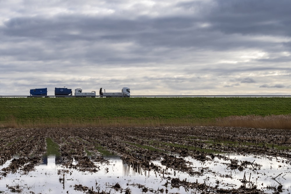 a tractor trailer is driving through a flooded field