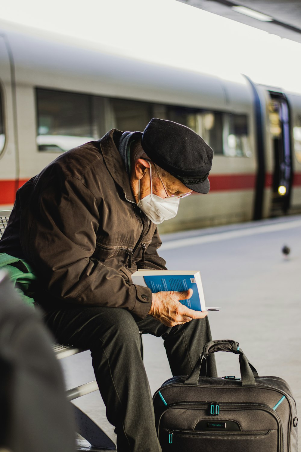 a man sitting on a bench next to a train